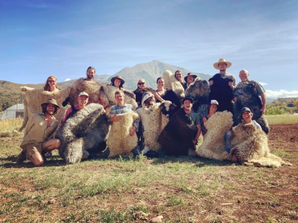 Group posing with sheepskins they tanned