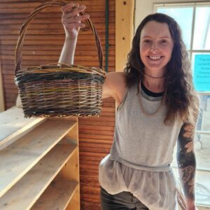 student holding up her completed willow basket